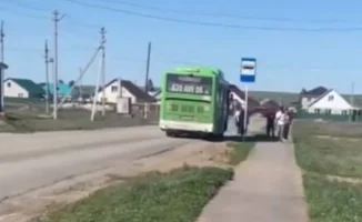 Жители города ожидают автобус на открытой остановке: задержка в расписании вызывает недовольство